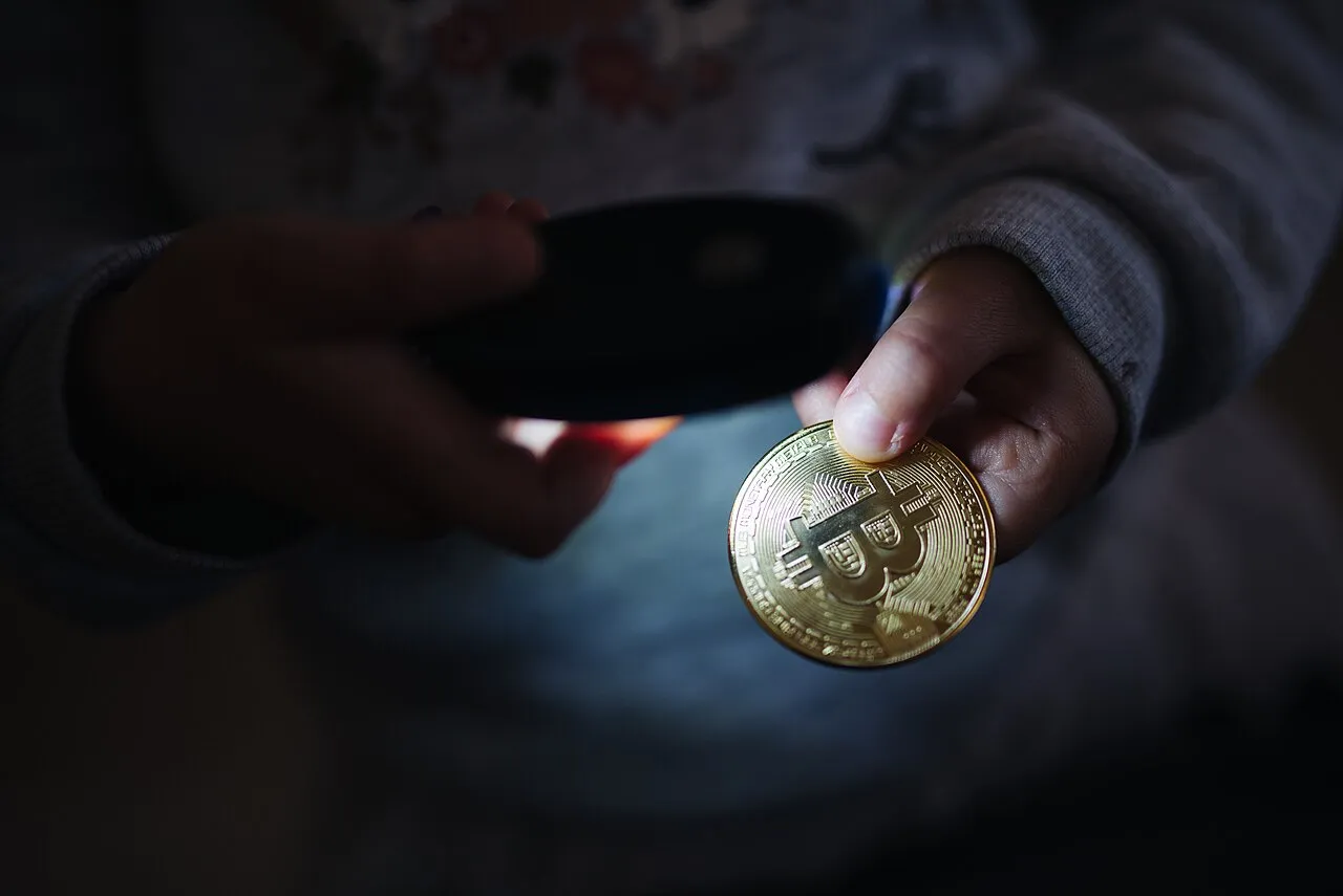 Young kid pointing light at the Bitcoin physical coin.jpg